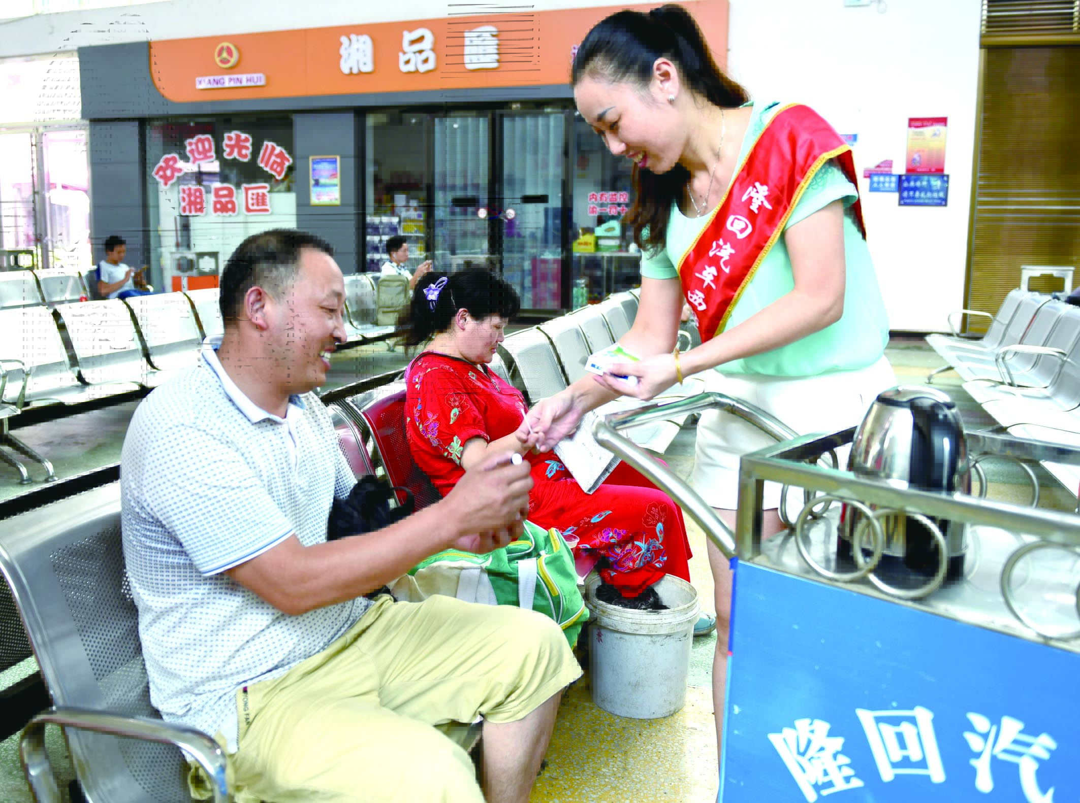 隆回分公司汽車西站工作人員正在為旅客免費(fèi)贈(zèng)送藿香正氣水。